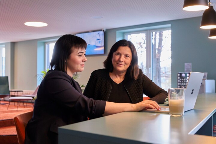 Zwei Mitarbeitende im lockeren Gespr&auml;ch bei einem Kaffee im gem&uuml;tlichen Empfangsbereich der TAS AG.