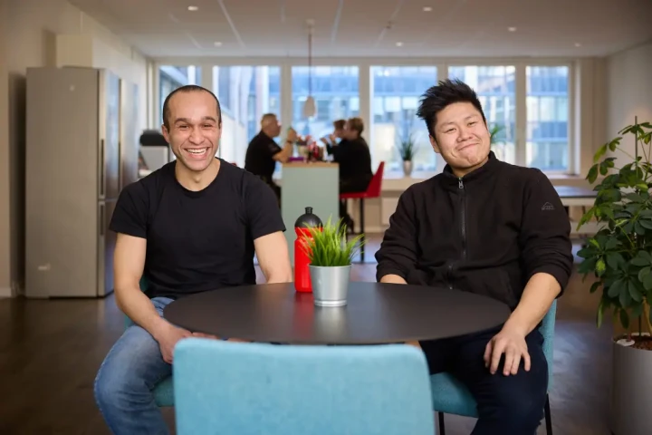 Zwei gutgelaunte Mitarbeitende im Pausenraum der TAS AG.